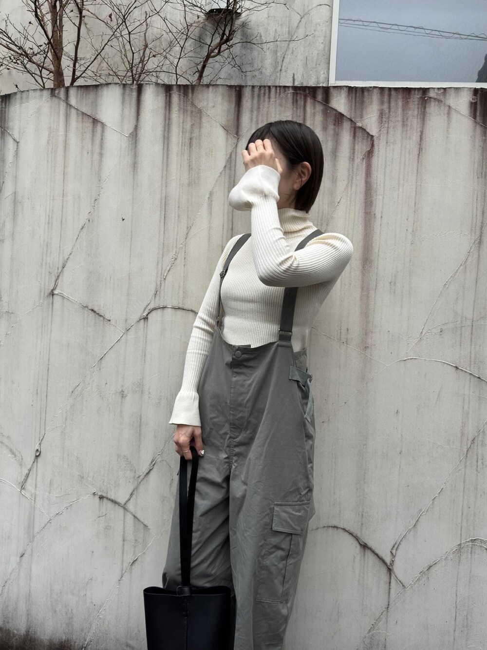 ホワイト系のニット/セーター、グリーン系のサロペット/オーバーオール、ブラック系のブーツを着用したレディースの冬コーディネートの3枚目の写真