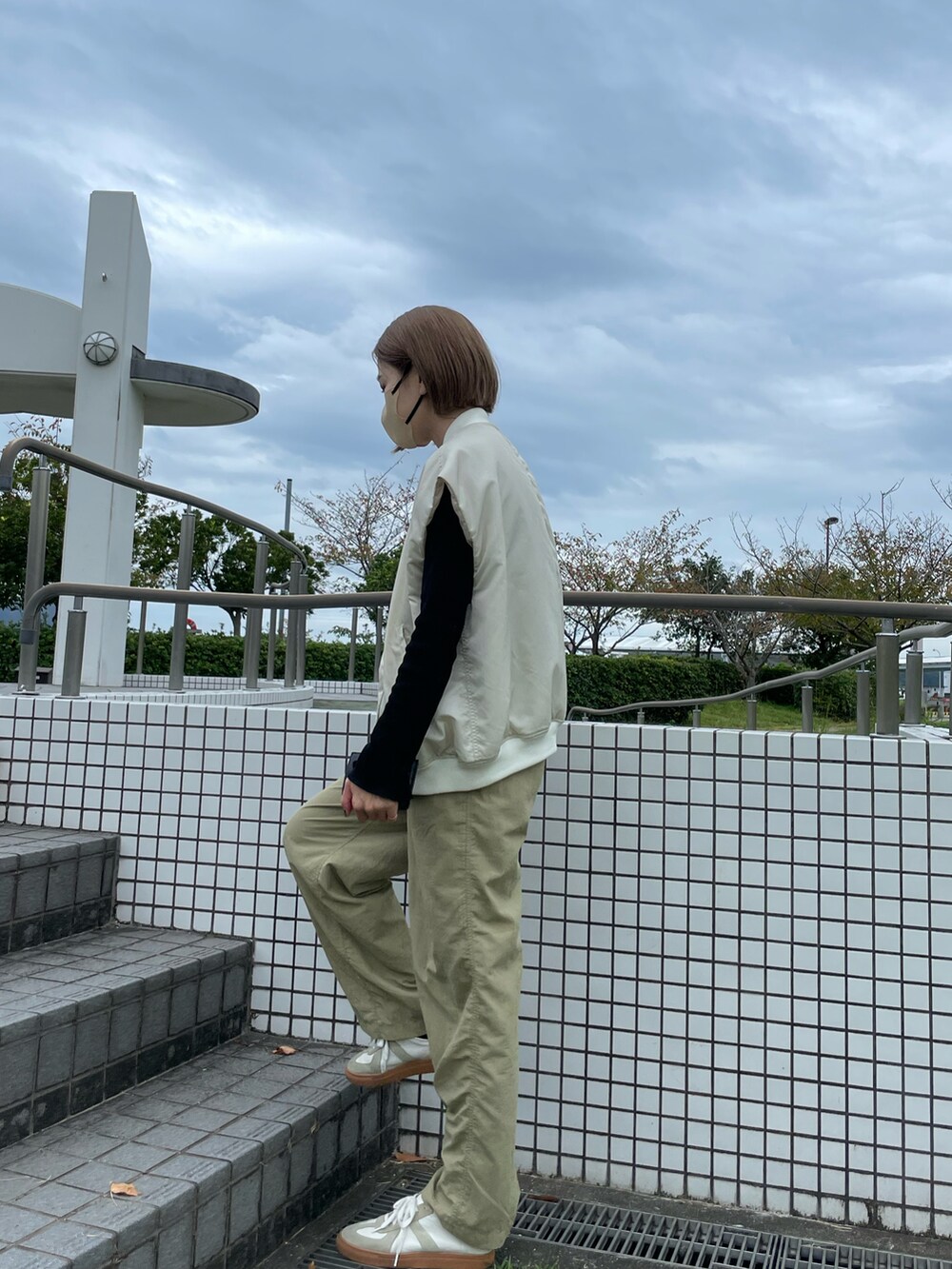 ホワイト系のダウンベスト、ブラック系のTシャツ/カットソー、ベージュ系のパンツを着用したレディースの秋コーディネートの3枚目の写真