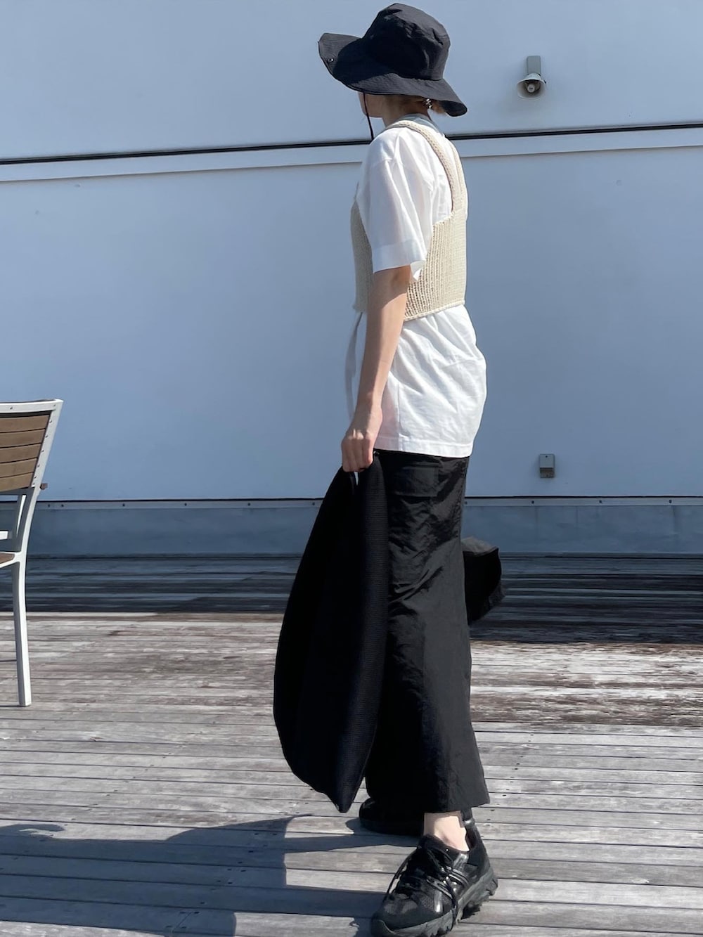 ホワイト系のベスト、ホワイト系のTシャツ/カットソー、ブラック系のスカートを着用したレディースの夏コーディネートの2枚目の写真