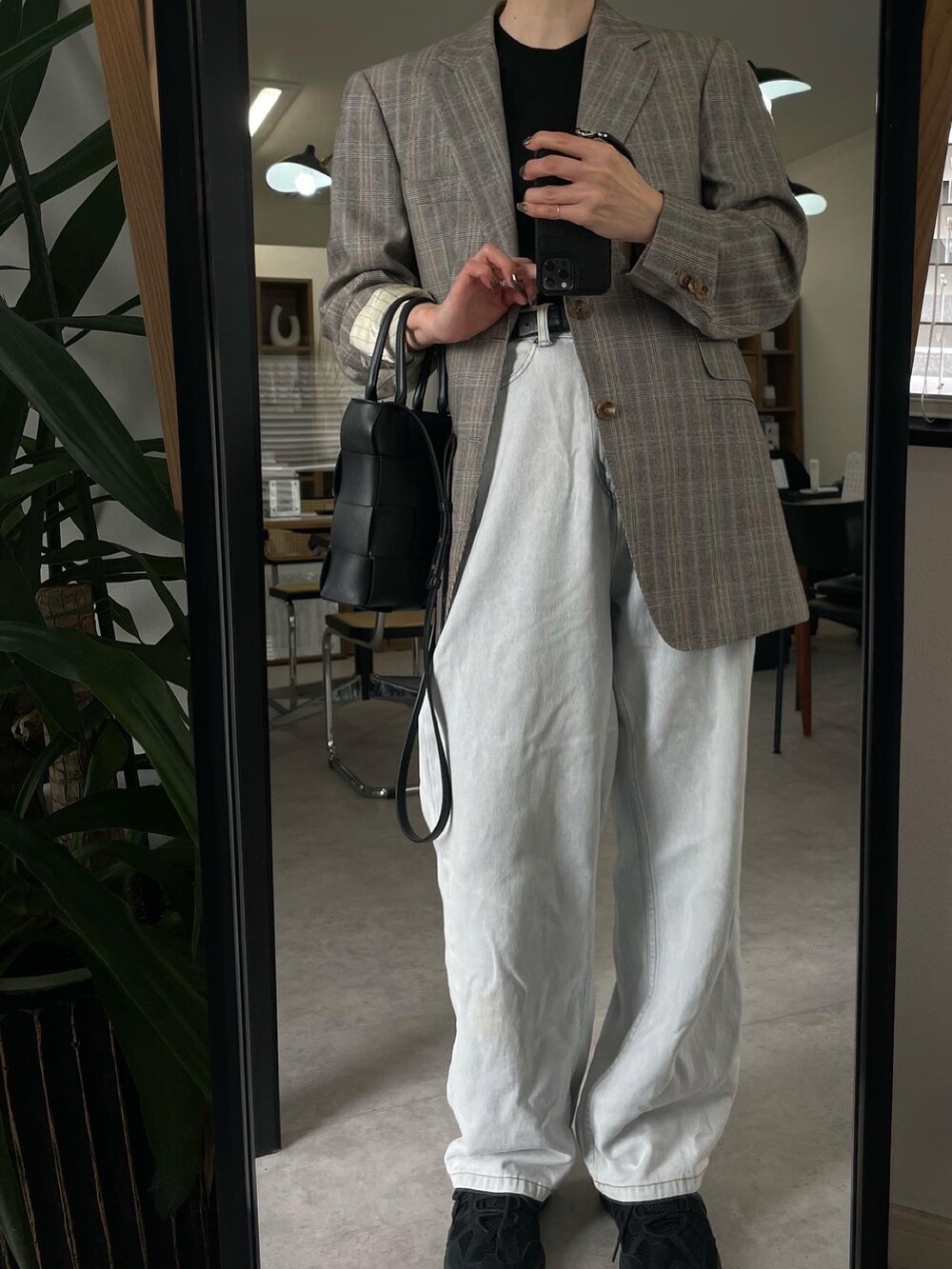 ブルー系のデニムパンツ、ブラック系のスニーカー、ブラック系のバッグを着用したレディースの春コーディネートの2枚目の写真