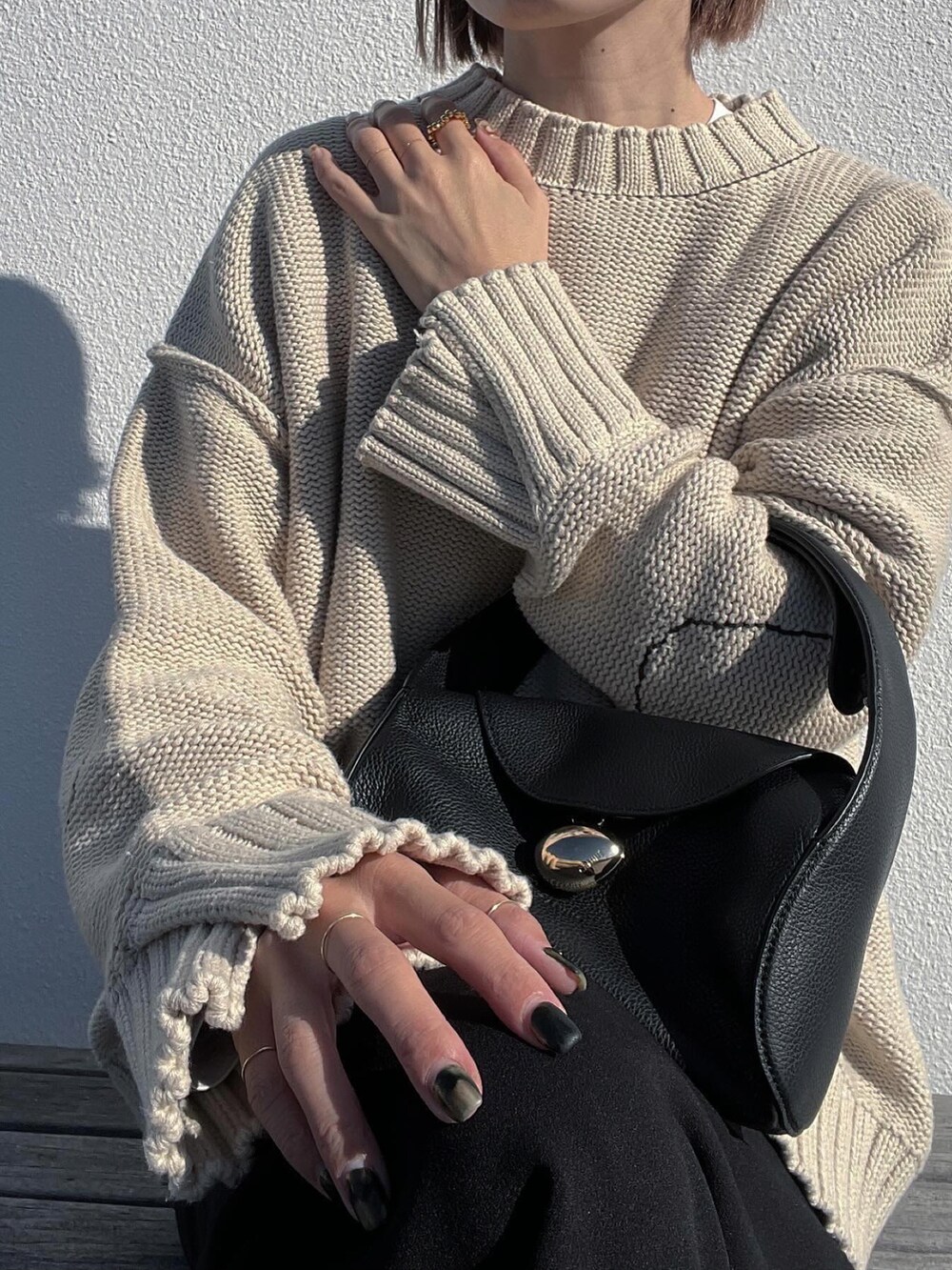 ベージュ系のニット/セーター、ブラック系のスカート、ブラック系のブーツを着用したレディースの秋コーディネートの4枚目の写真