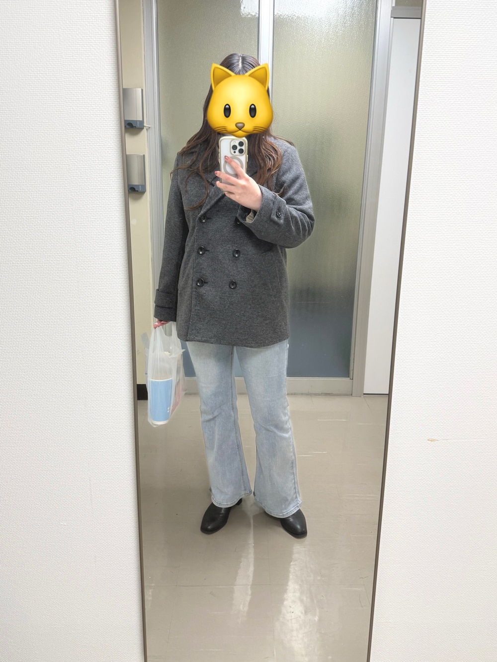 グレー系のピーコート、ブルー系のデニムパンツ、ブラック系のブーツを着用したレディースの冬コーディネートの3枚目の写真