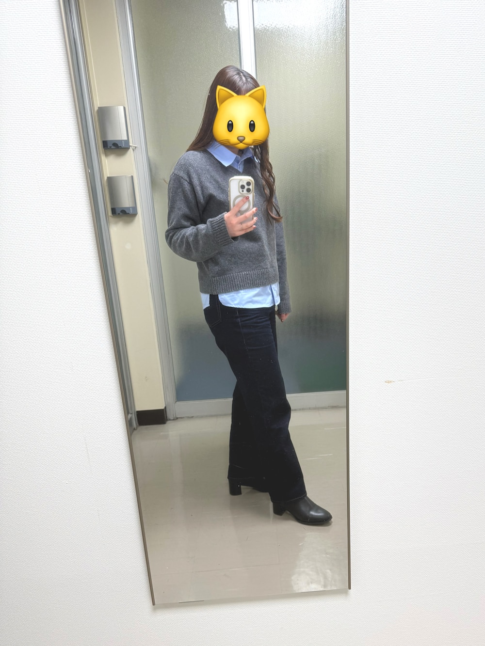 グレー系のトップス、ブルー系のデニムパンツ、ブラック系のブーツを着用したレディースの冬コーディネートの2枚目の写真