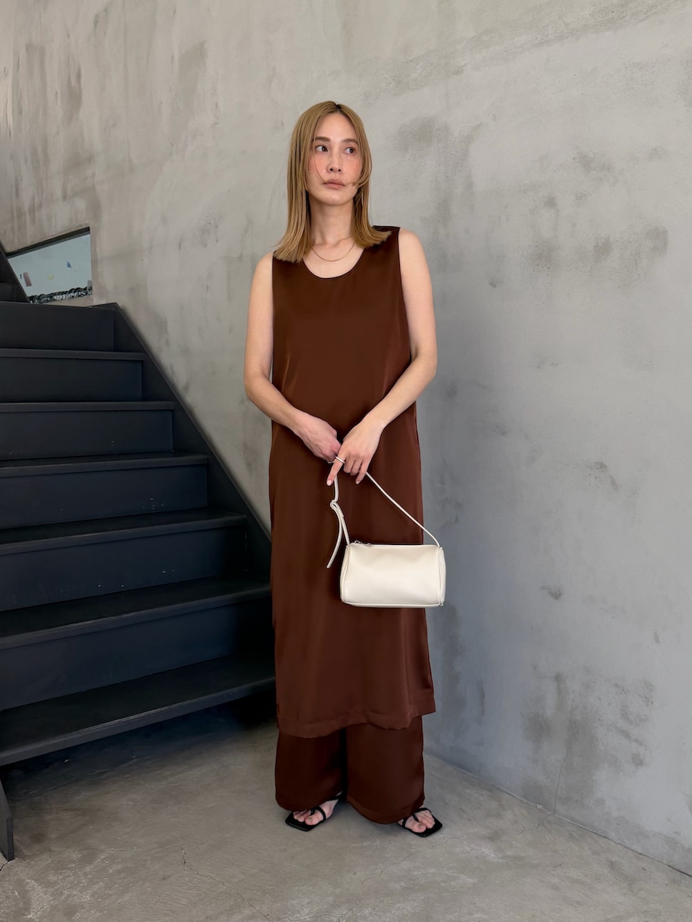 ホワイト系のハンドバッグ、ブラック系のサンダル、ホワイト系のキャミソールを着用したレディースの春コーディネートの3枚目の写真