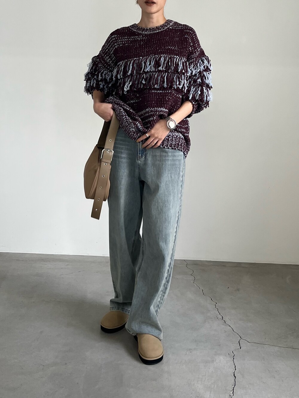 ブラウン系のニット/セーター、ブルー系のデニムパンツ、ベージュ系のショルダーバッグを着用したレディースの秋コーディネートの2枚目の写真