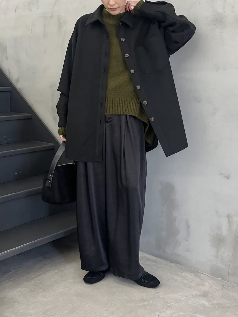 ブラック系のカバーオール、グリーン系のニット/セーター、ブラック系のスラックスを着用したレディースの秋コーディネートの3枚目の写真