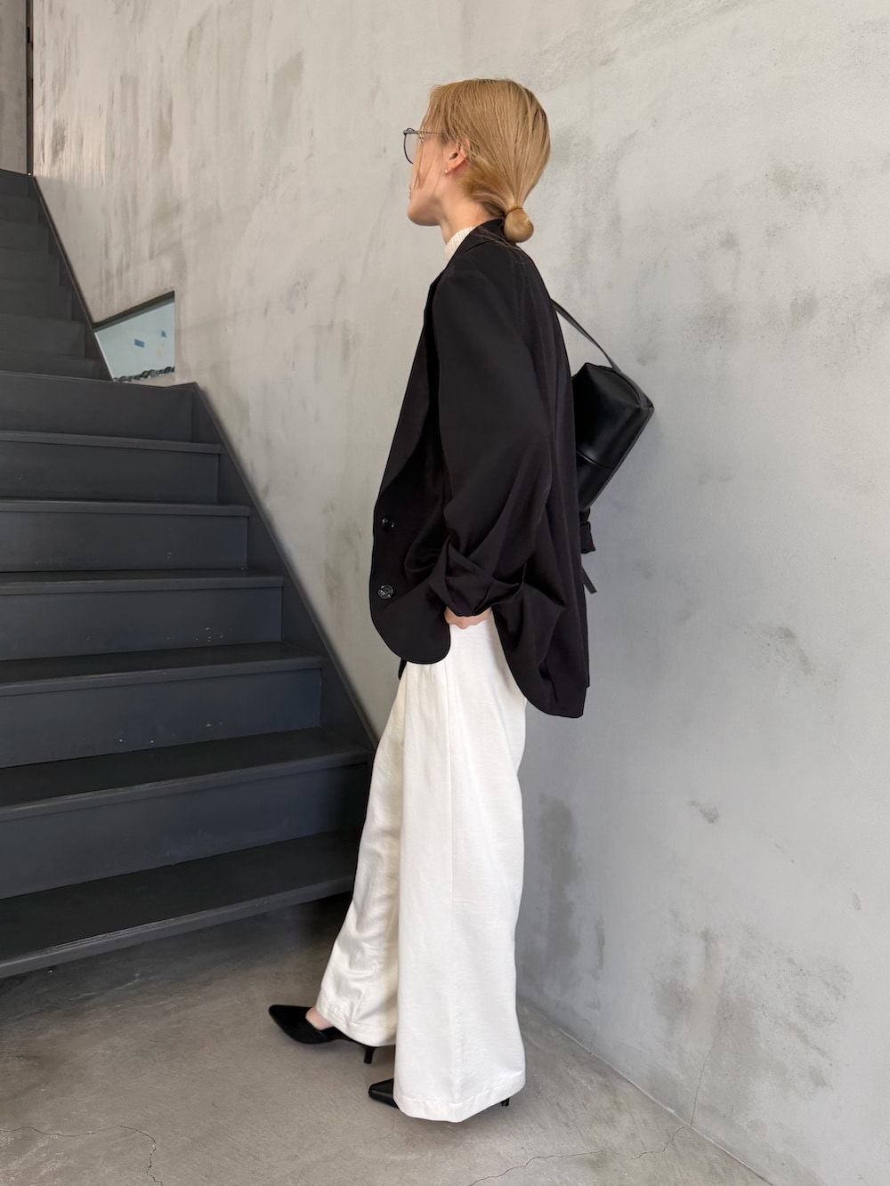 ブラック系のテーラードジャケット、ホワイト系のニット/セーター、ブラック系のショルダーバッグを着用したレディースの春コーディネートの7枚目の写真