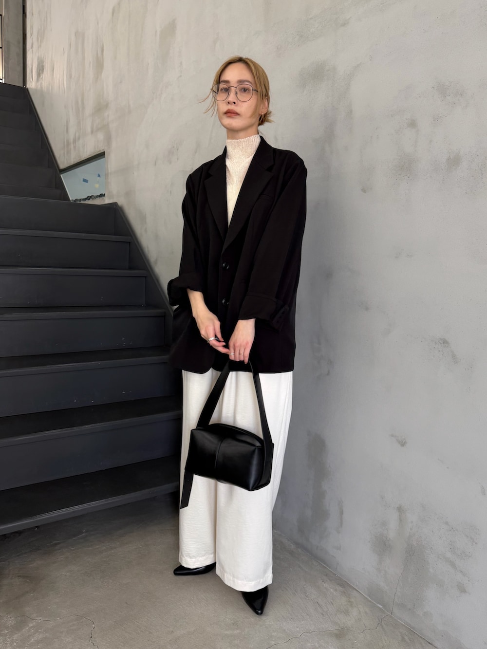 ブラック系のテーラードジャケット、ホワイト系のニット/セーター、ブラック系のショルダーバッグを着用したレディースの春コーディネートの2枚目の写真