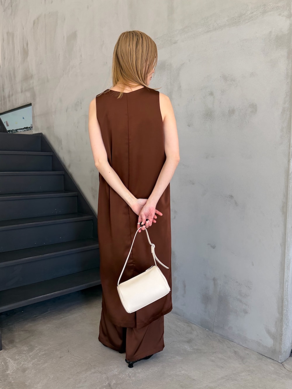 ホワイト系のハンドバッグ、ブラック系のサンダル、ホワイト系のキャミソールを着用したレディースの春コーディネートの5枚目の写真