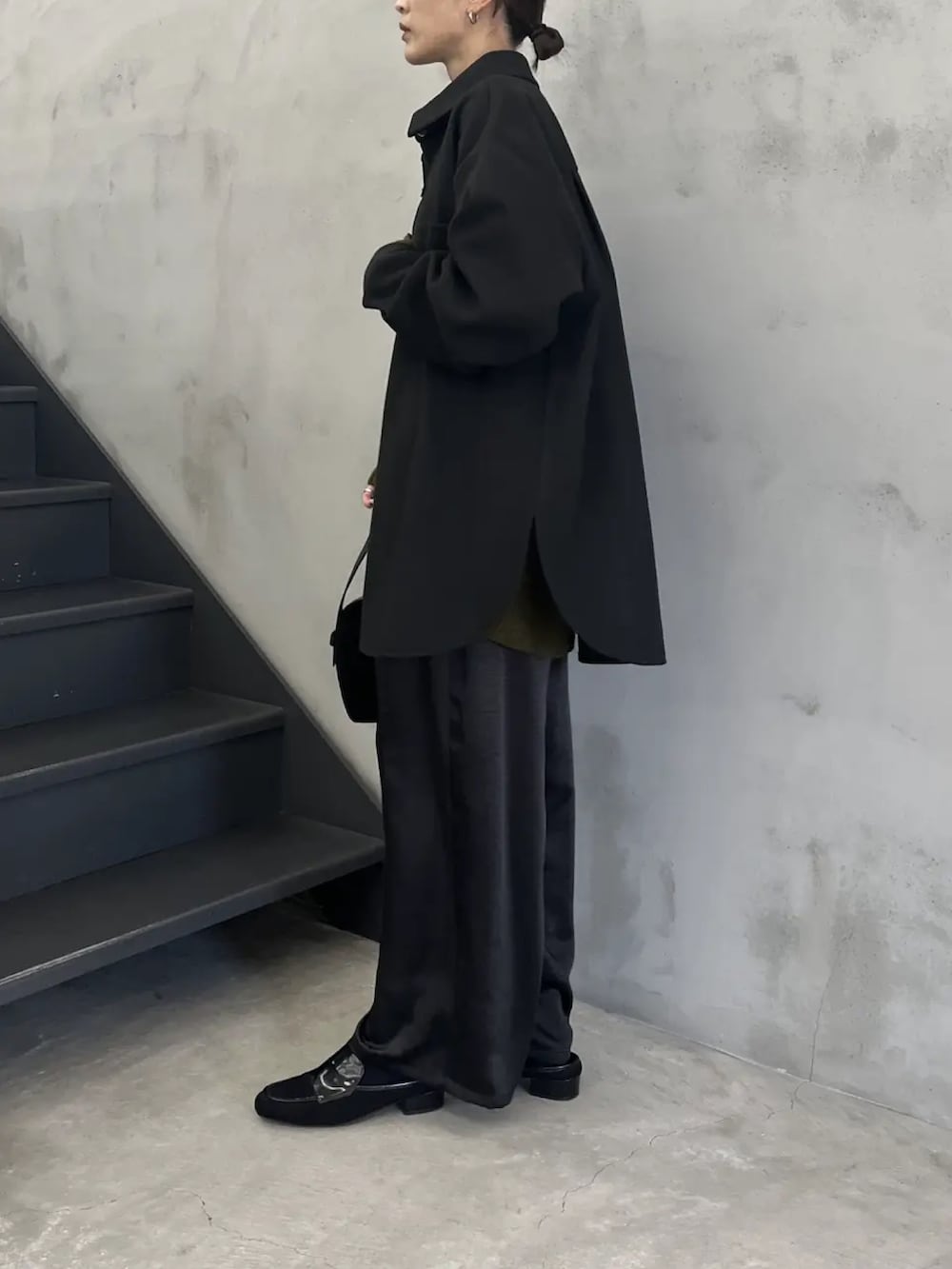 ブラック系のカバーオール、グリーン系のニット/セーター、ブラック系のスラックスを着用したレディースの秋コーディネートの4枚目の写真