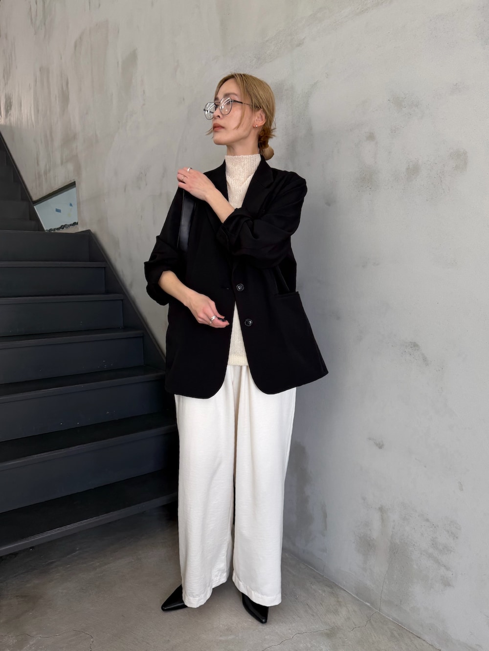 ブラック系のテーラードジャケット、ホワイト系のニット/セーター、ブラック系のショルダーバッグを着用したレディースの春コーディネートの4枚目の写真