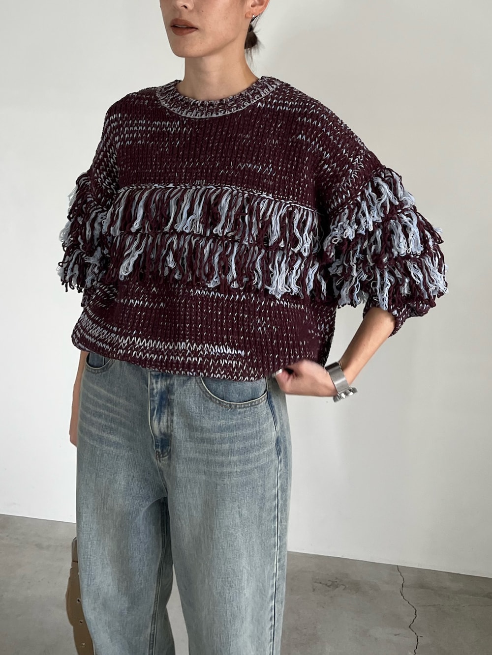 ブラウン系のニット/セーター、ブルー系のデニムパンツ、ベージュ系のショルダーバッグを着用したレディースの秋コーディネートの5枚目の写真