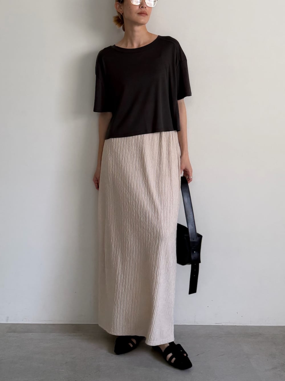 グレー系のTシャツ/カットソー、ベージュ系のスカート、ブラック系のサンダルを着用したレディースの春コーディネートの6枚目の写真