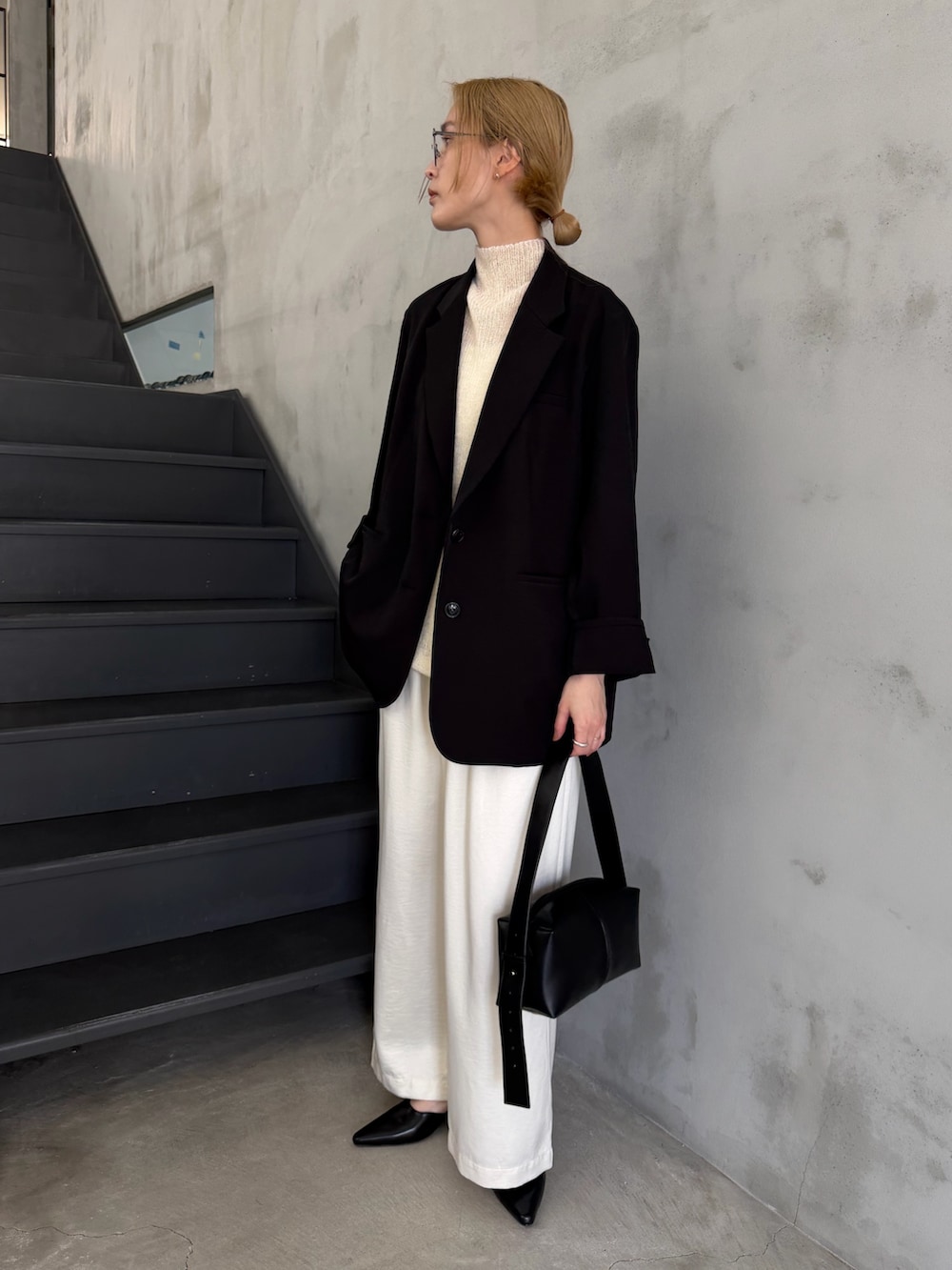 ブラック系のテーラードジャケット、ホワイト系のニット/セーター、ブラック系のショルダーバッグを着用したレディースの春コーディネートの5枚目の写真
