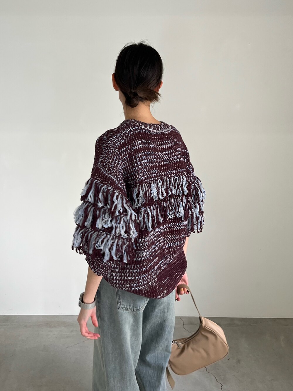 ブラウン系のニット/セーター、ブルー系のデニムパンツ、ベージュ系のショルダーバッグを着用したレディースの秋コーディネートの4枚目の写真