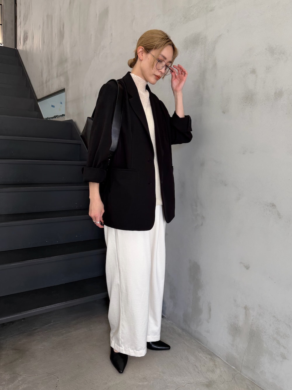 ブラック系のテーラードジャケット、ホワイト系のニット/セーター、ブラック系のショルダーバッグを着用したレディースの春コーディネートの3枚目の写真