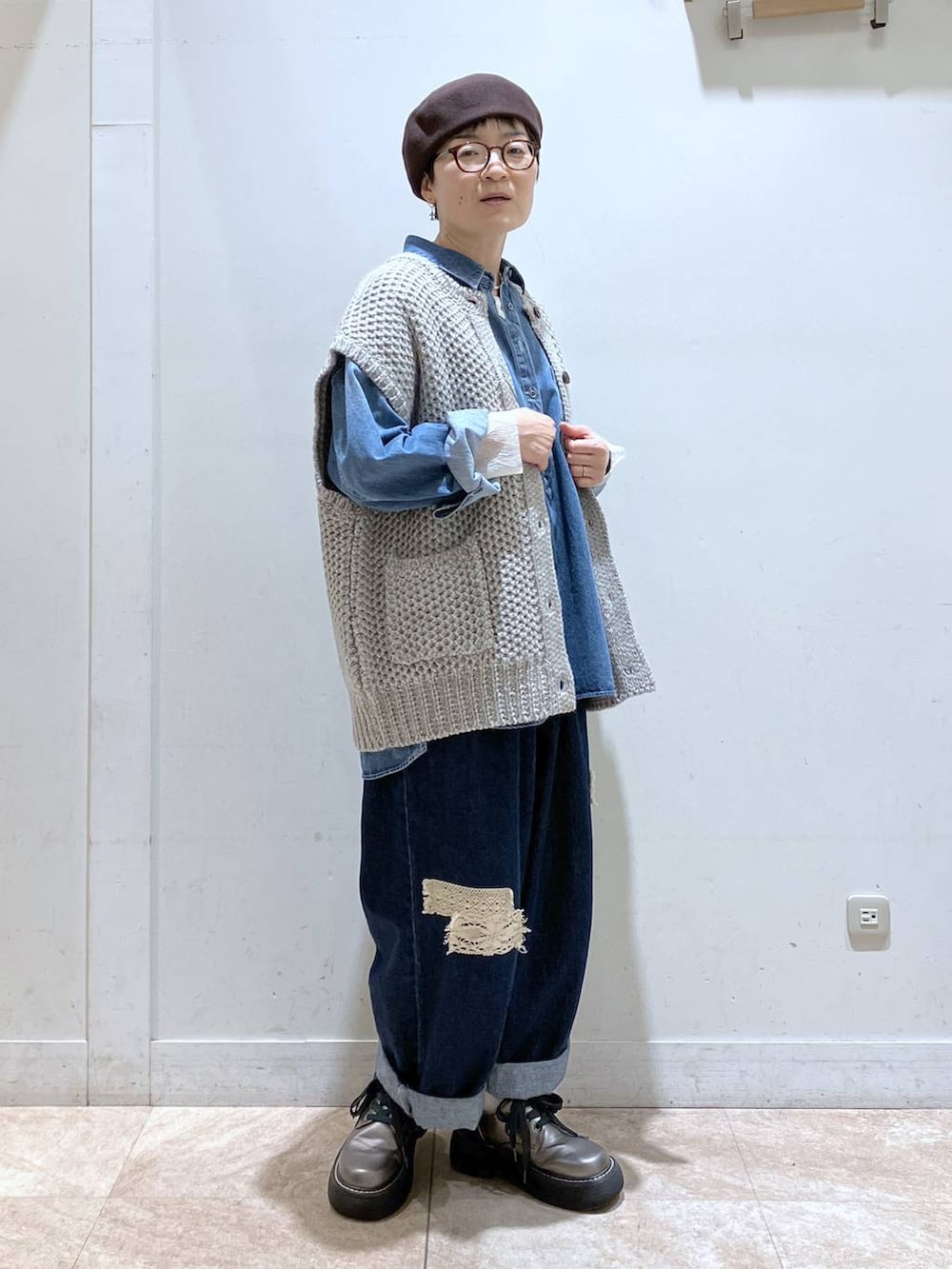 グレー系のニット/セーター、ブルー系のシャツ/ブラウス、ブルー系のデニムパンツを着用したレディースの秋コーディネートの5枚目の写真