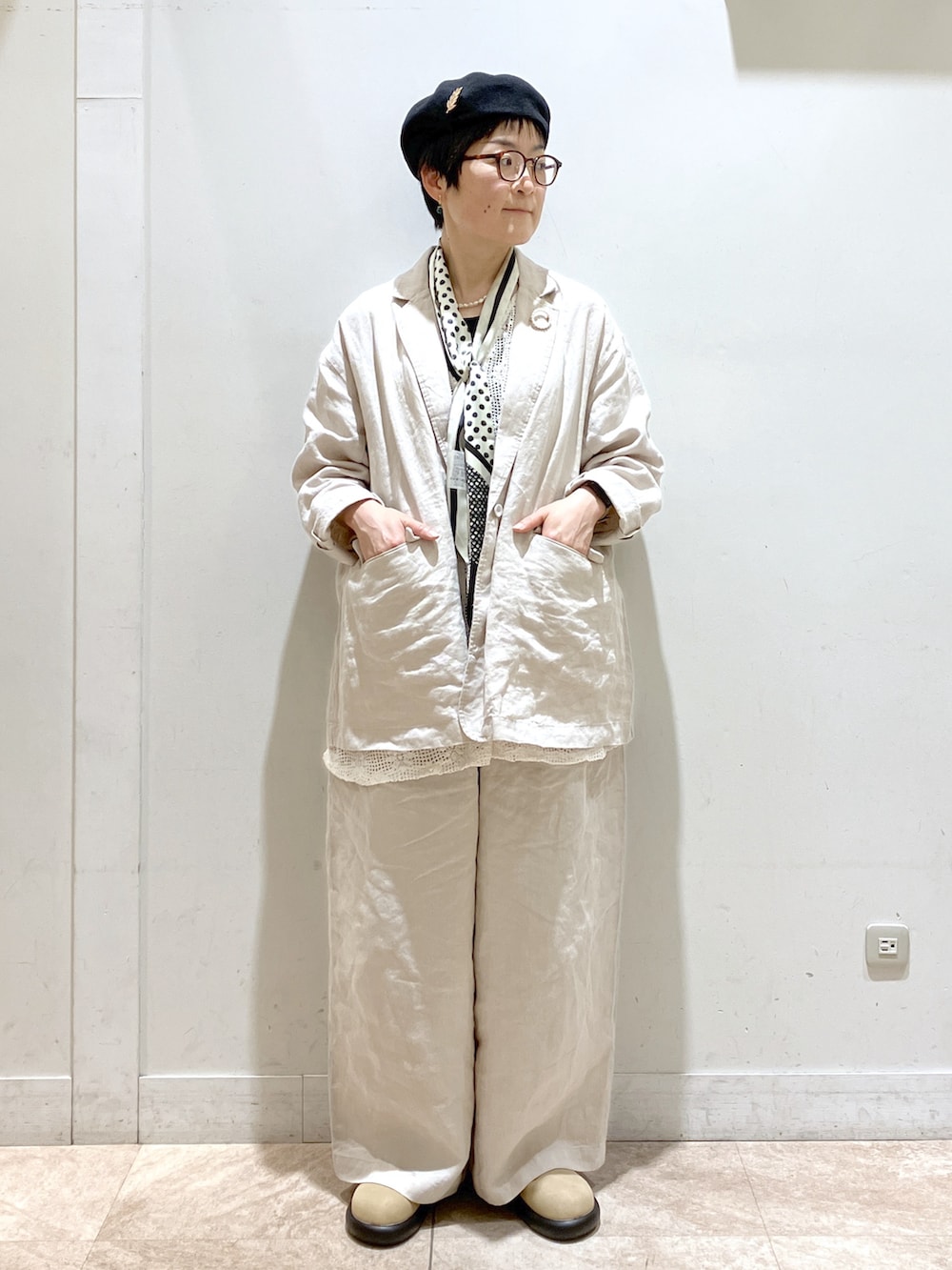 ベージュ系のスーツセット、ベージュ系のサンダル、ブラック系のタンクトップを着用したレディースの冬コーディネートの3枚目の写真