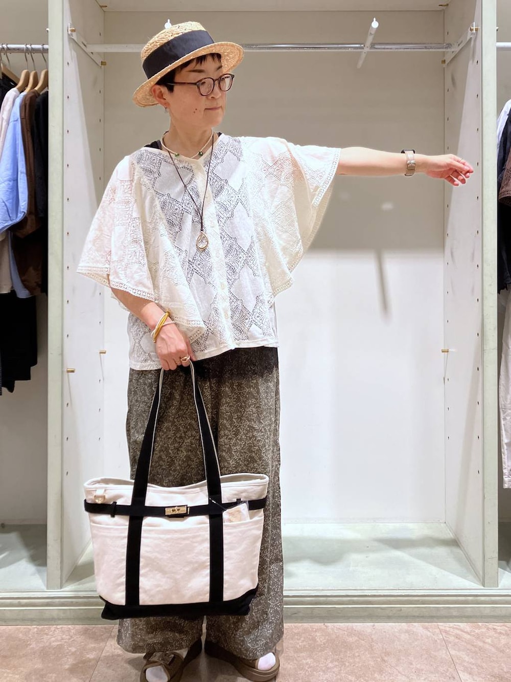ベージュ系のシャツ/ブラウス、その他のサンダル、ブラック系のトートバッグを着用したレディースの夏コーディネートの2枚目の写真