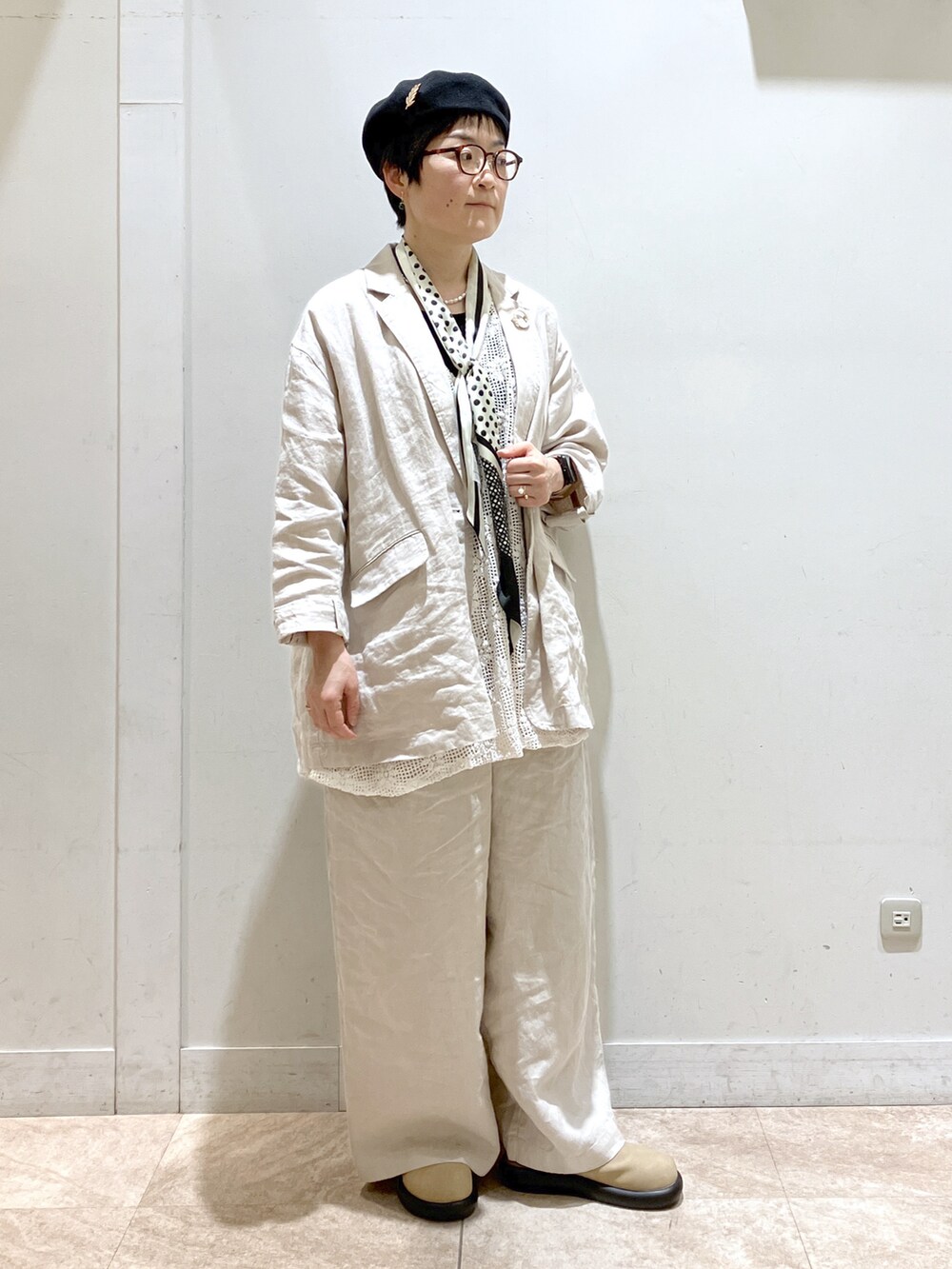 ベージュ系のスーツセット、ベージュ系のサンダル、ブラック系のタンクトップを着用したレディースの冬コーディネートの2枚目の写真