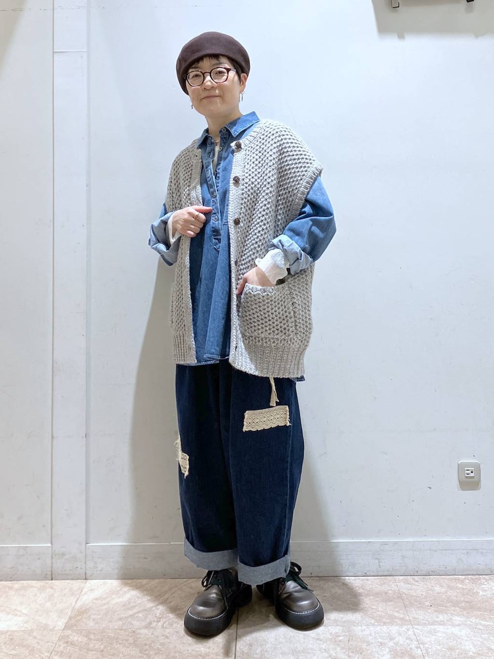 グレー系のニット/セーター、ブルー系のシャツ/ブラウス、ブルー系のデニムパンツを着用したレディースの秋コーディネートの3枚目の写真