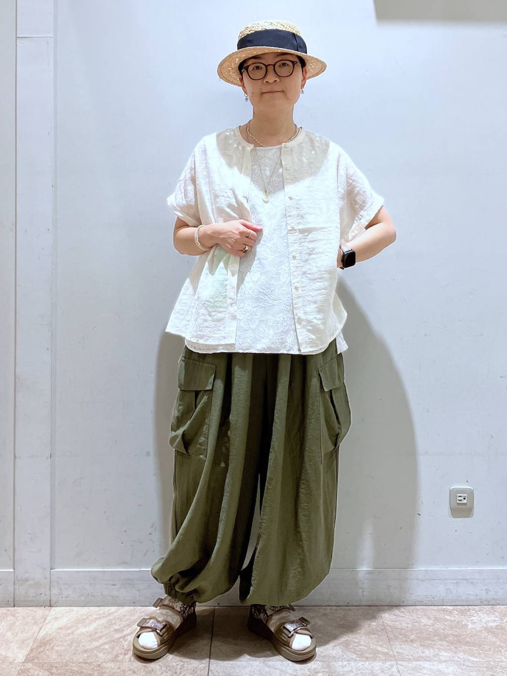 グリーン系のカーゴパンツ、その他のサンダル、ベージュ系のTシャツ/カットソーを着用したレディースの夏コーディネートの2枚目の写真