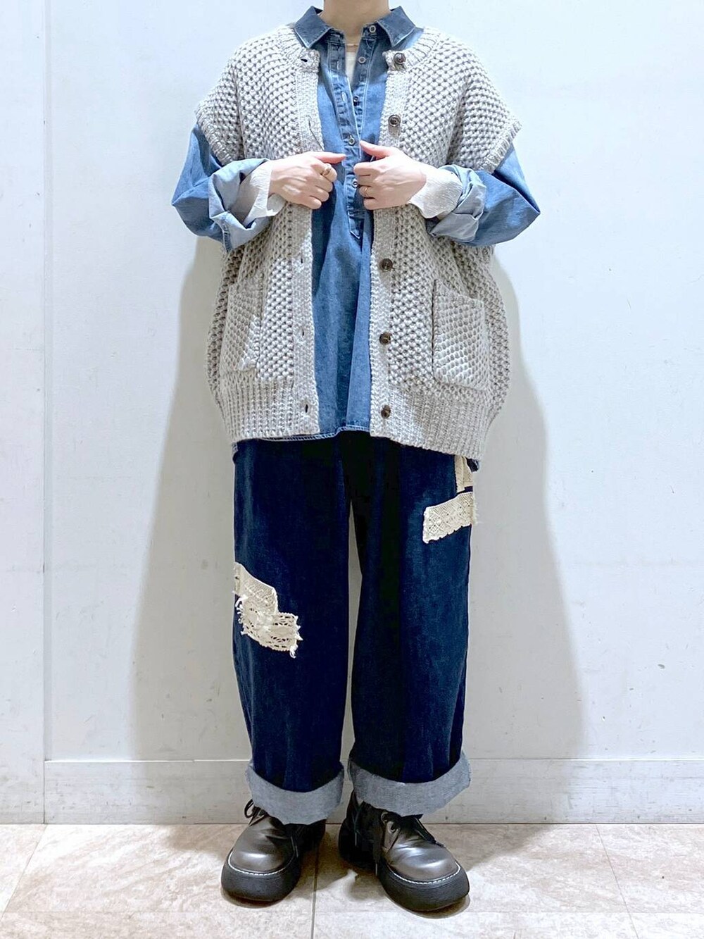 グレー系のニット/セーター、ブルー系のシャツ/ブラウス、ブルー系のデニムパンツを着用したレディースの秋コーディネートの2枚目の写真