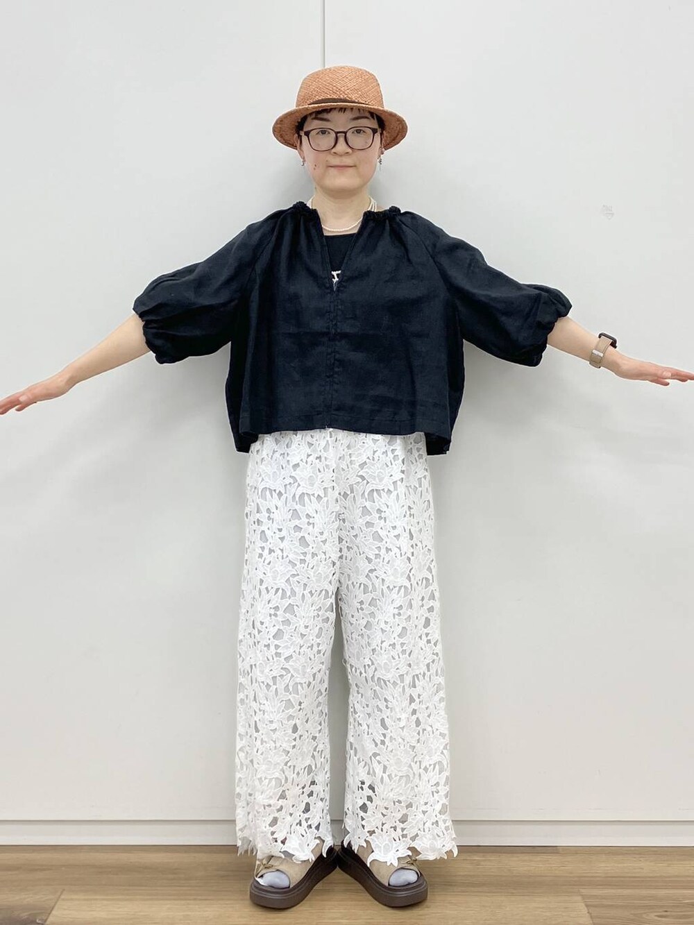 ブラック系のタンクトップ、ベージュ系のサンダル、ホワイト系のネックレスを着用したレディースの春コーディネートの2枚目の写真