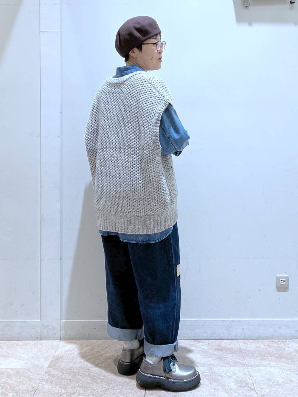 グレー系のニット/セーター、ブルー系のシャツ/ブラウス、ブルー系のデニムパンツを着用したレディースの秋コーディネートの4枚目の写真
