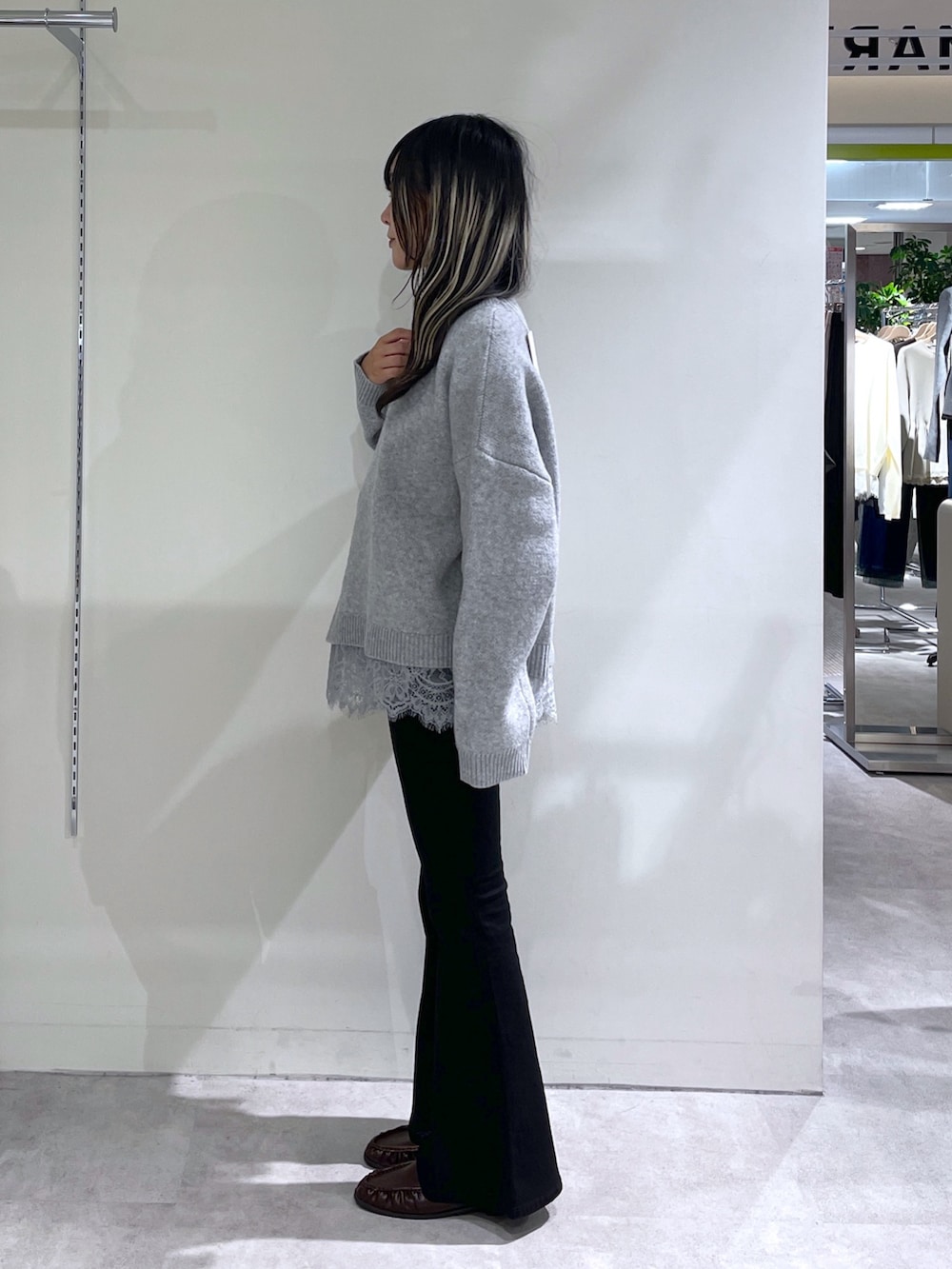 グレー系のニット/セーター、ブラック系のデニムパンツ、ホワイト系のボストンバッグを着用したレディースの秋コーディネートの2枚目の写真