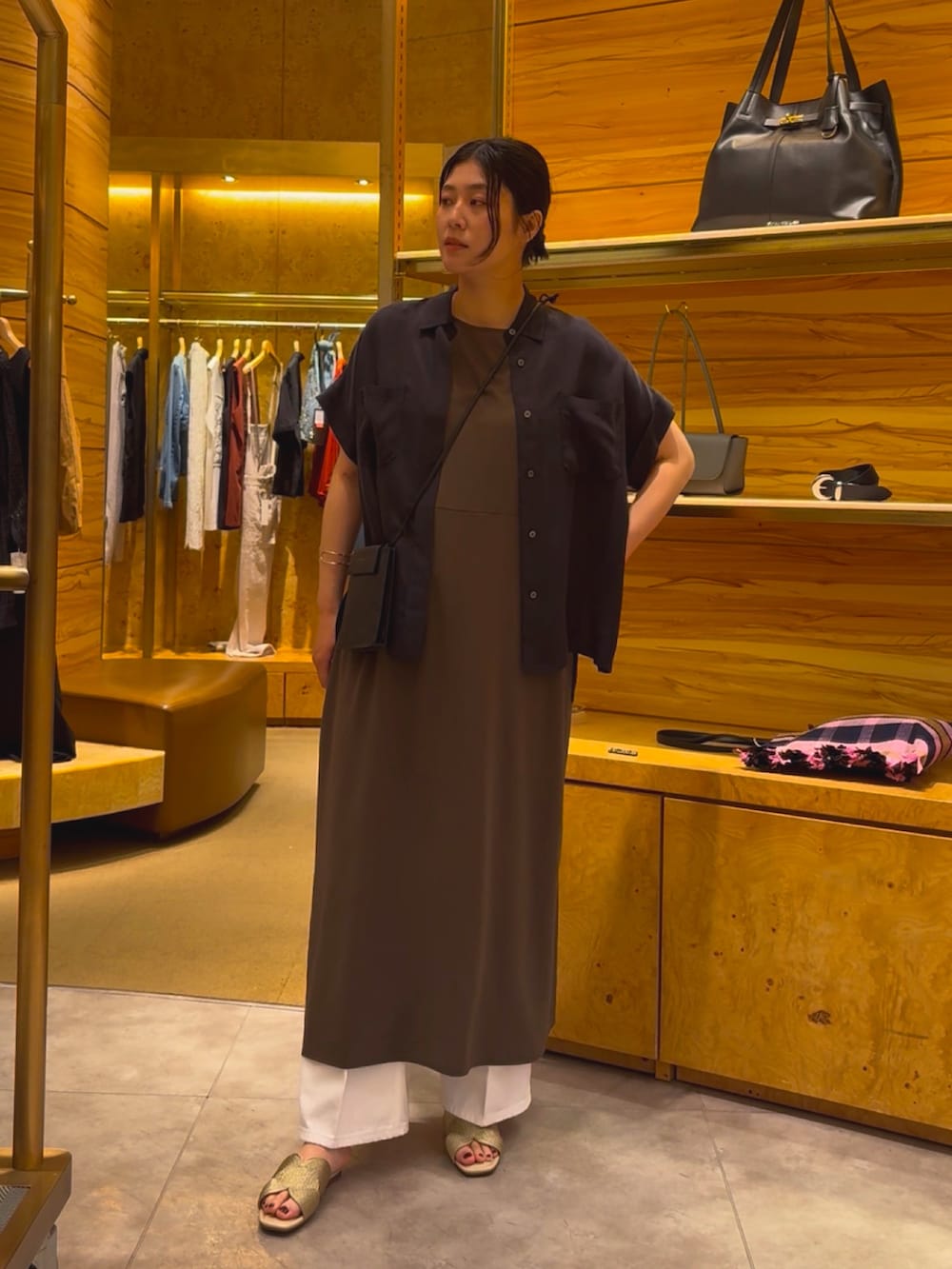 グレー系のワンピース、ホワイト系のデニムパンツ、ゴールド系のその他シューズを着用したレディースの春コーディネートの2枚目の写真