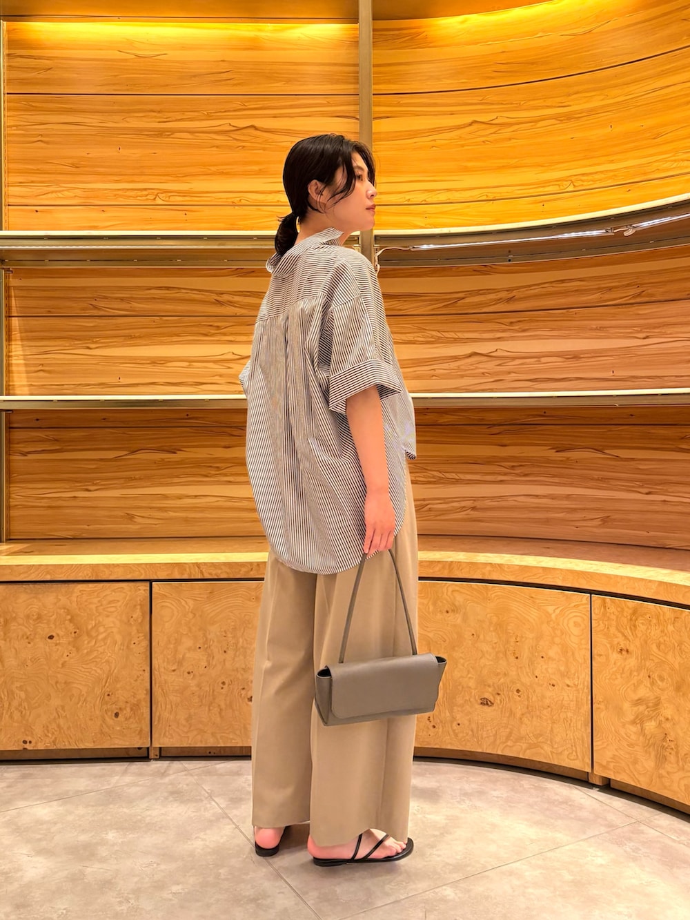 ベージュ系のその他パンツ、ブルー系のシャツ/ブラウス、グレー系のハンドバッグを着用したレディースの夏コーディネートの2枚目の写真
