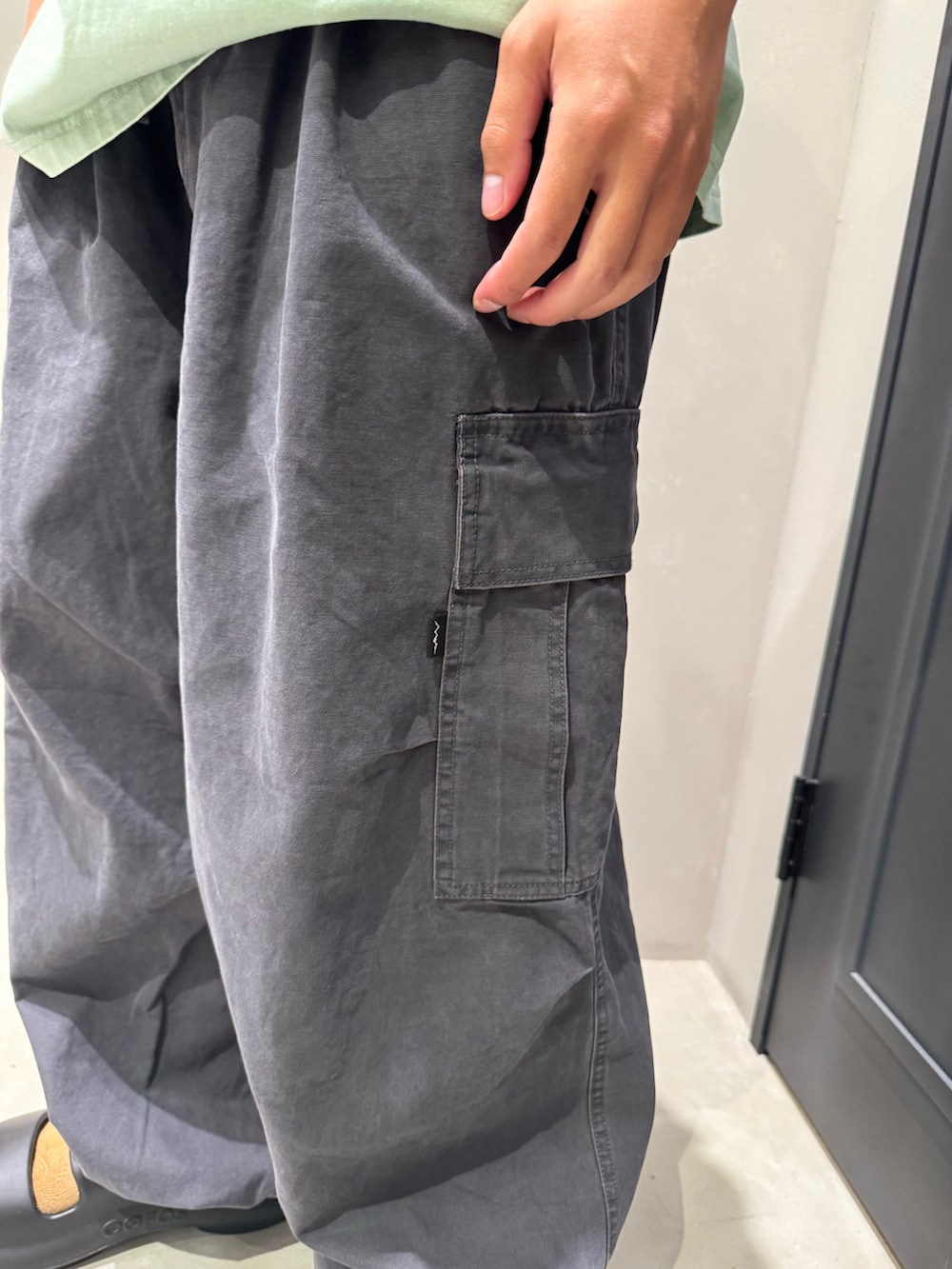 グリーン系のTシャツ/カットソー、グレー系のカーゴパンツ、ブラック系のサンダルを着用したメンズの夏コーディネートの6枚目の写真