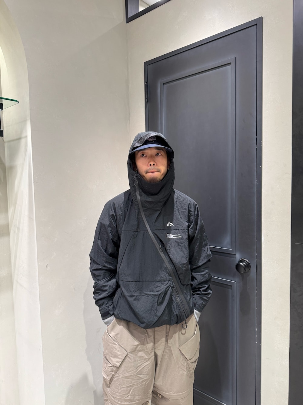 ブラック系のマウンテンパーカー、ベージュ系のカーゴパンツ、ブラック系のサンダルを着用したメンズの夏コーディネートの2枚目の写真