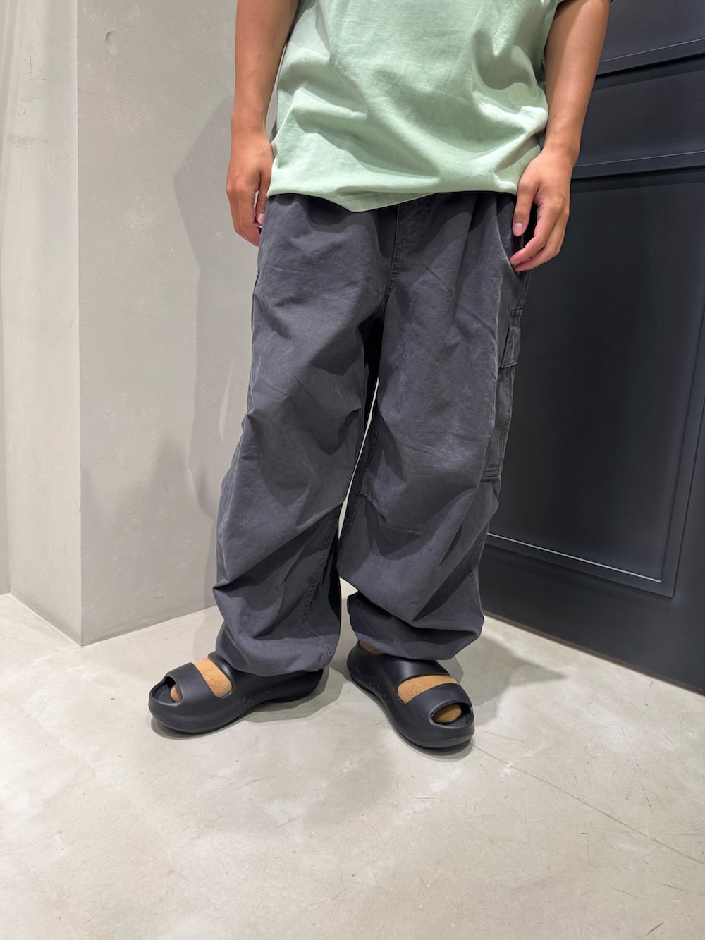 グリーン系のTシャツ/カットソー、グレー系のカーゴパンツ、ブラック系のサンダルを着用したメンズの夏コーディネートの5枚目の写真