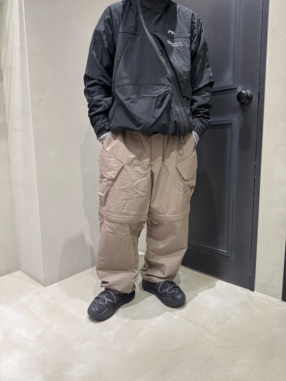 ブラック系のマウンテンパーカー、ベージュ系のカーゴパンツ、ブラック系のサンダルを着用したメンズの夏コーディネートの3枚目の写真