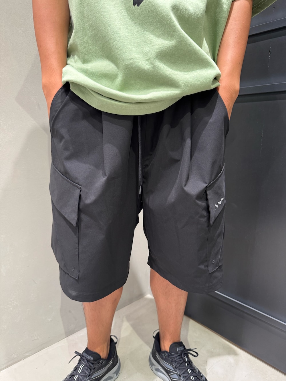 ブラック系のその他パンツ、ブラック系のスニーカー、グリーン系のTシャツ/カットソーを着用したメンズの夏コーディネートの3枚目の写真