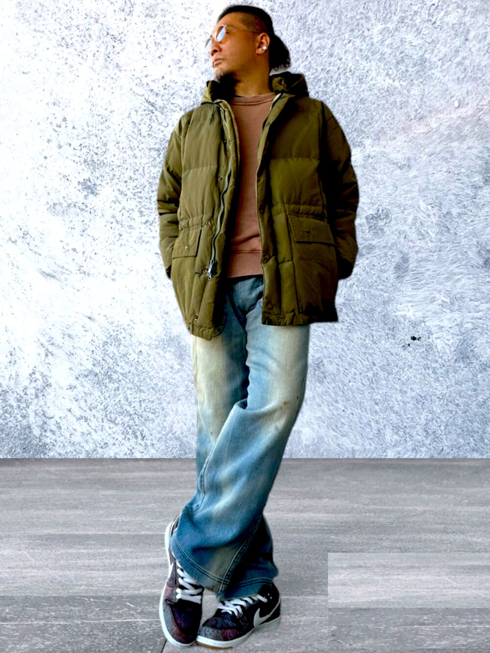 ブラウン系のダウンジャケット/コート、ブラウン系のスウェット、ブルー系のデニムパンツを着用したメンズの冬コーディネートの2枚目の写真