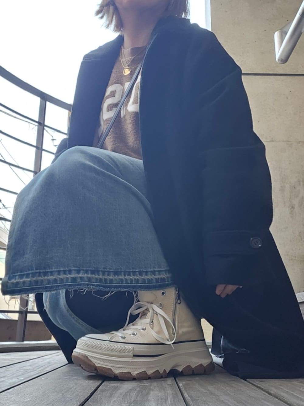 ブラック系のショルダーバッグ、ブラック系のステンカラーコート、ベージュ系のスウェットを着用したレディースの冬コーディネートの2枚目の写真