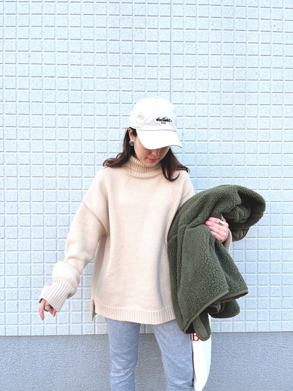 グリーン系のブルゾン、ホワイト系のニット/セーターを着用したレディースの春コーディネートの2枚目の写真
