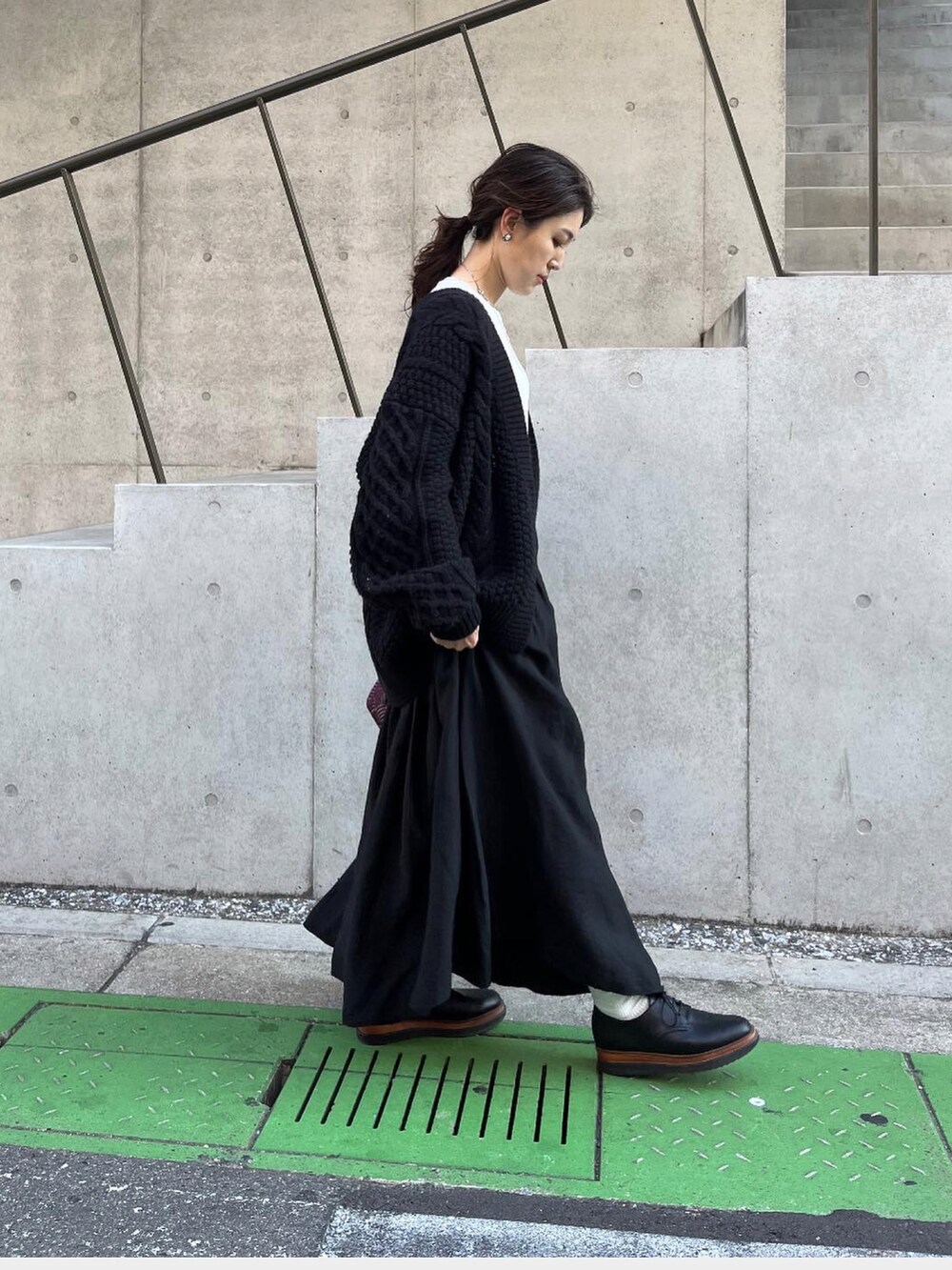 ブラック系のスカート、ブラック系のカーディガン/ボレロ、シルバー系のネックレスを着用したレディースの秋コーディネートの2枚目の写真