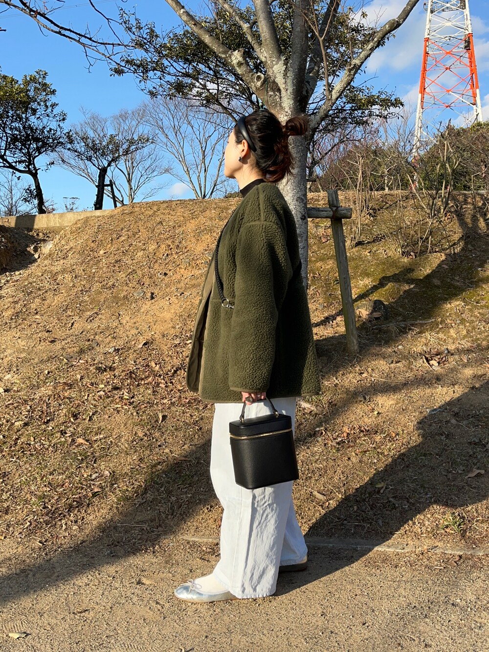 ブラック系のショルダーバッグ、ブルー系のデニムパンツ、シルバー系のバレエシューズを着用したレディースの冬コーディネートの2枚目の写真