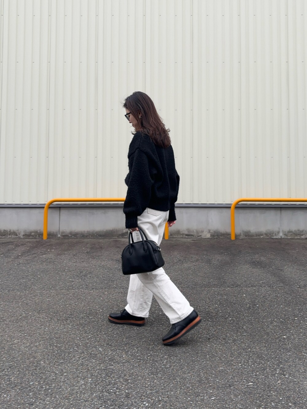 ブラック系のニット/セーター、ホワイト系のデニムパンツ、ホワイト系のベルトを着用したレディースの冬コーディネートの2枚目の写真