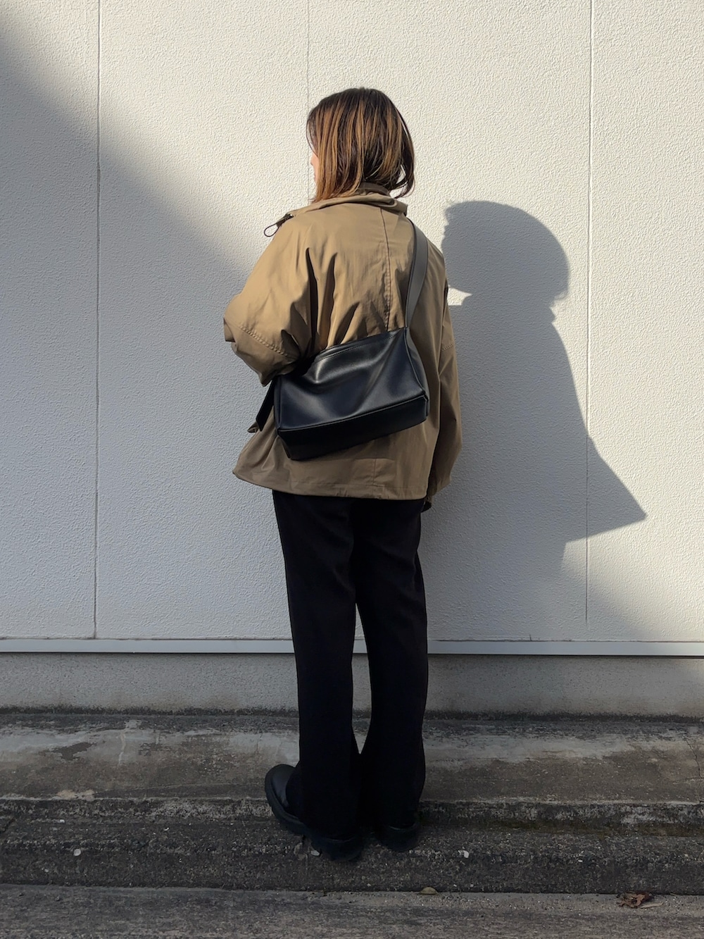 ブラウン系のブルゾン、ブラック系のショルダーバッグ、ブルー系のTシャツ/カットソーを着用したレディースの春コーディネートの3枚目の写真