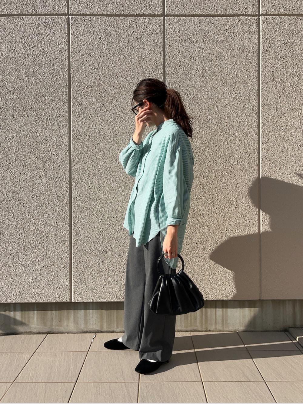 ブラック系のハンドバッグ、グリーン系のシャツ/ブラウス、グレー系のパンツを着用したレディースの秋コーディネートの2枚目の写真