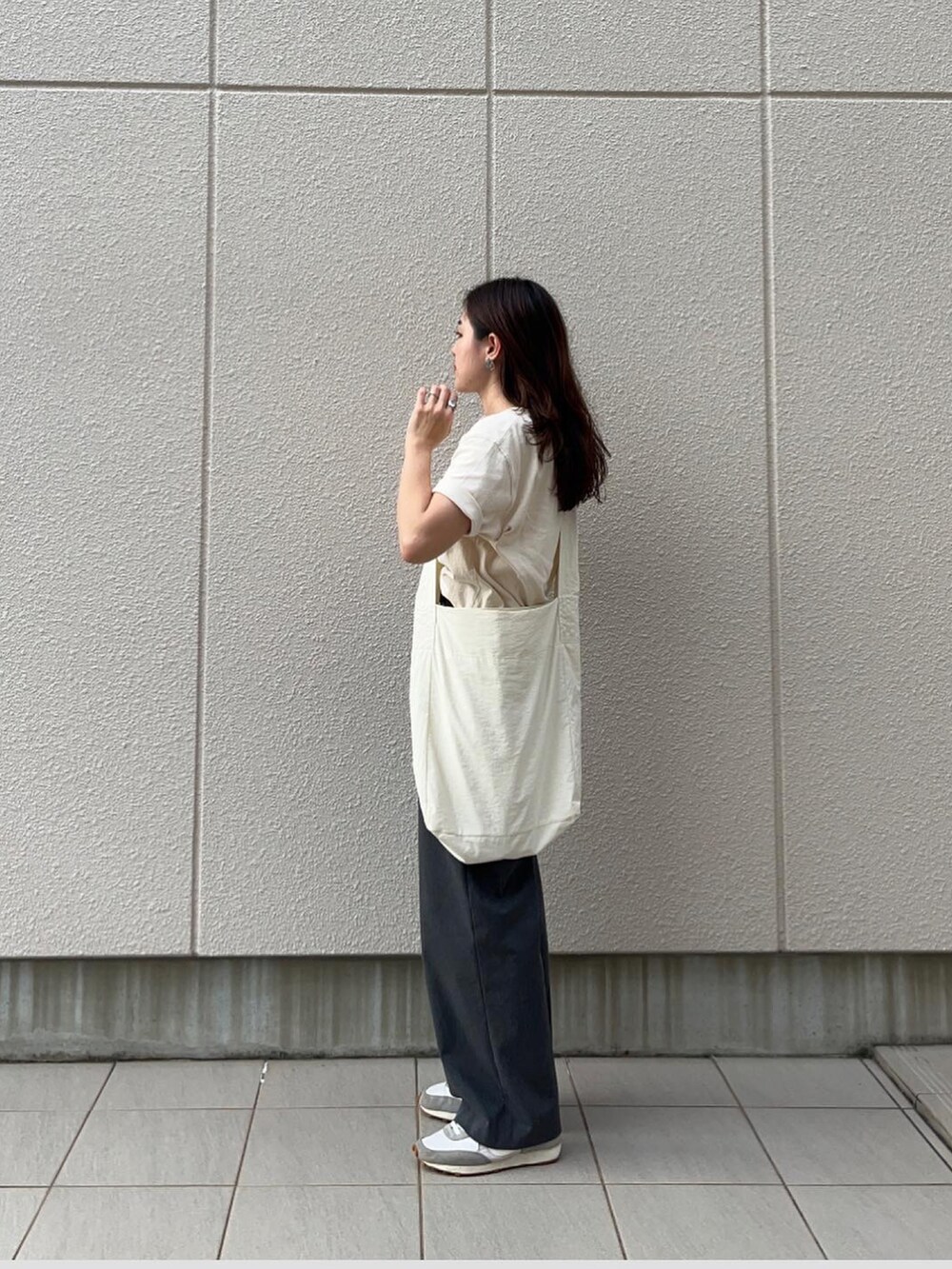 ベージュ系のTシャツ/カットソー、ホワイト系のショルダーバッグ、グレー系のパンツを着用したレディースの秋コーディネートの2枚目の写真