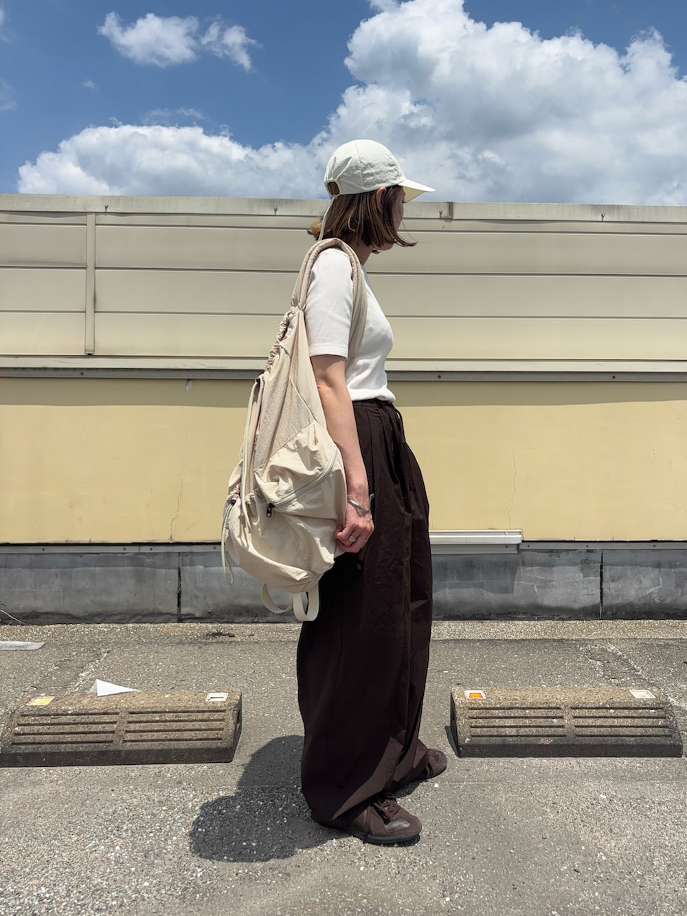 ブラウン系のその他パンツ、ブラウン系のスニーカー、ホワイト系のキャップを着用したレディースの春コーディネートの2枚目の写真