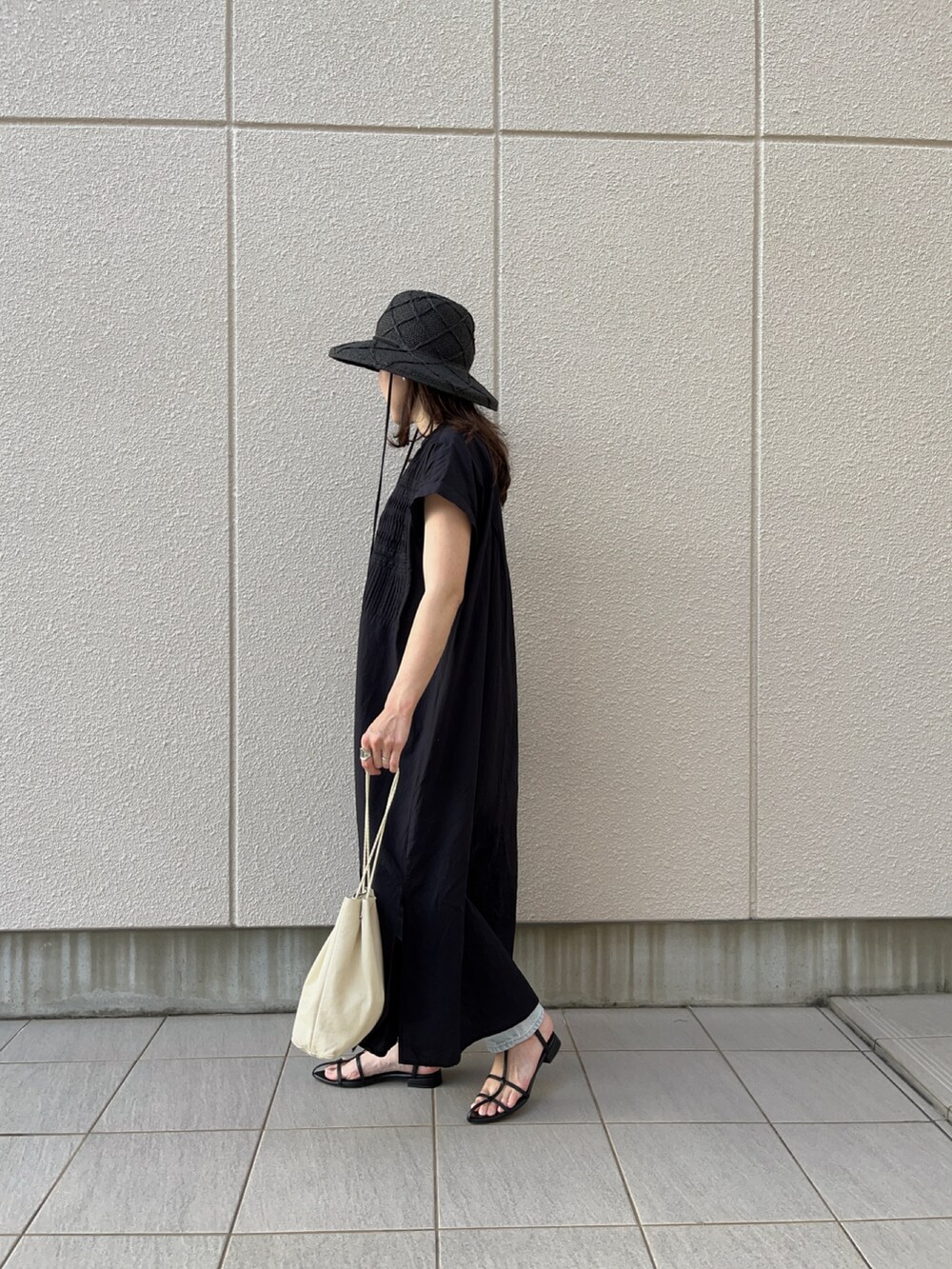 ブラック系のシャツワンピース、ブルー系のデニムパンツ、ブラック系のハットを着用したレディースの秋コーディネートの2枚目の写真