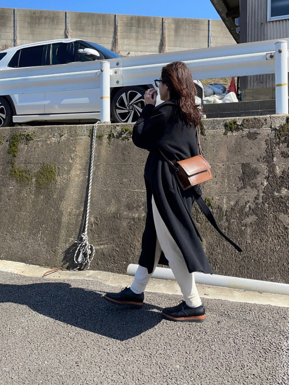 ホワイト系のスウェットパンツ、ブラック系のニット/セーター、ブラウン系のショルダーバッグを着用したレディースの春コーディネートの2枚目の写真