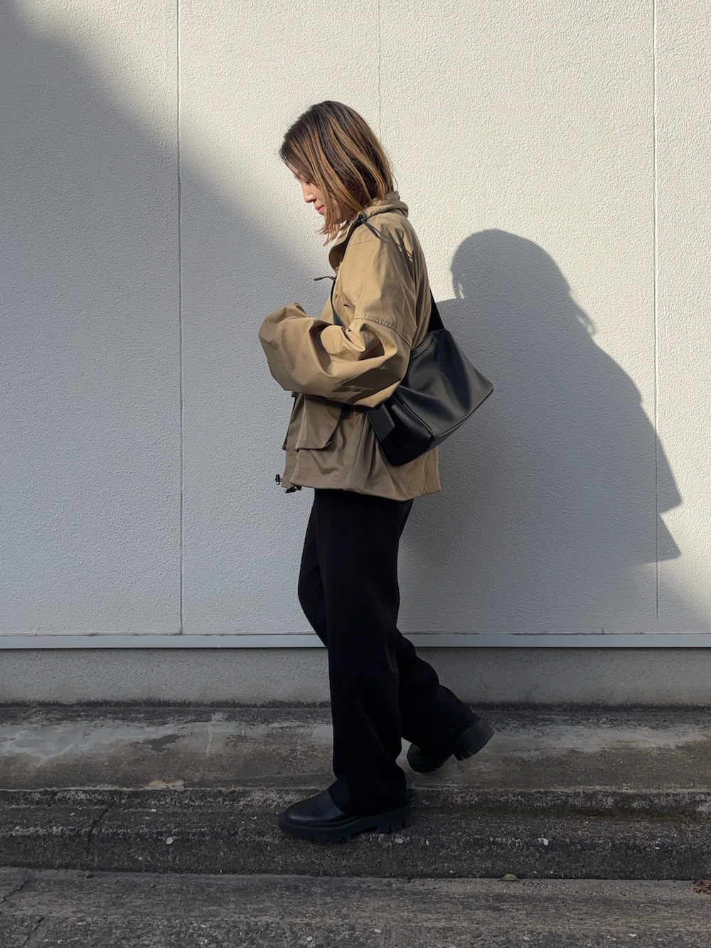 ブラウン系のブルゾン、ブラック系のショルダーバッグ、ブルー系のTシャツ/カットソーを着用したレディースの春コーディネートの2枚目の写真